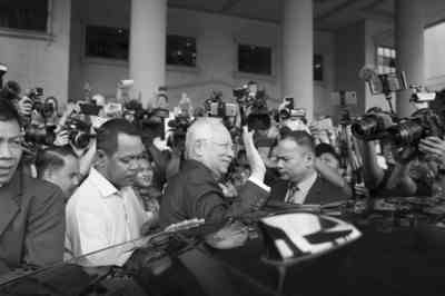 12月12日，在马来西亚吉隆坡，马来西亚前总理纳吉布（中）离开法院时向人们挥手。新华社